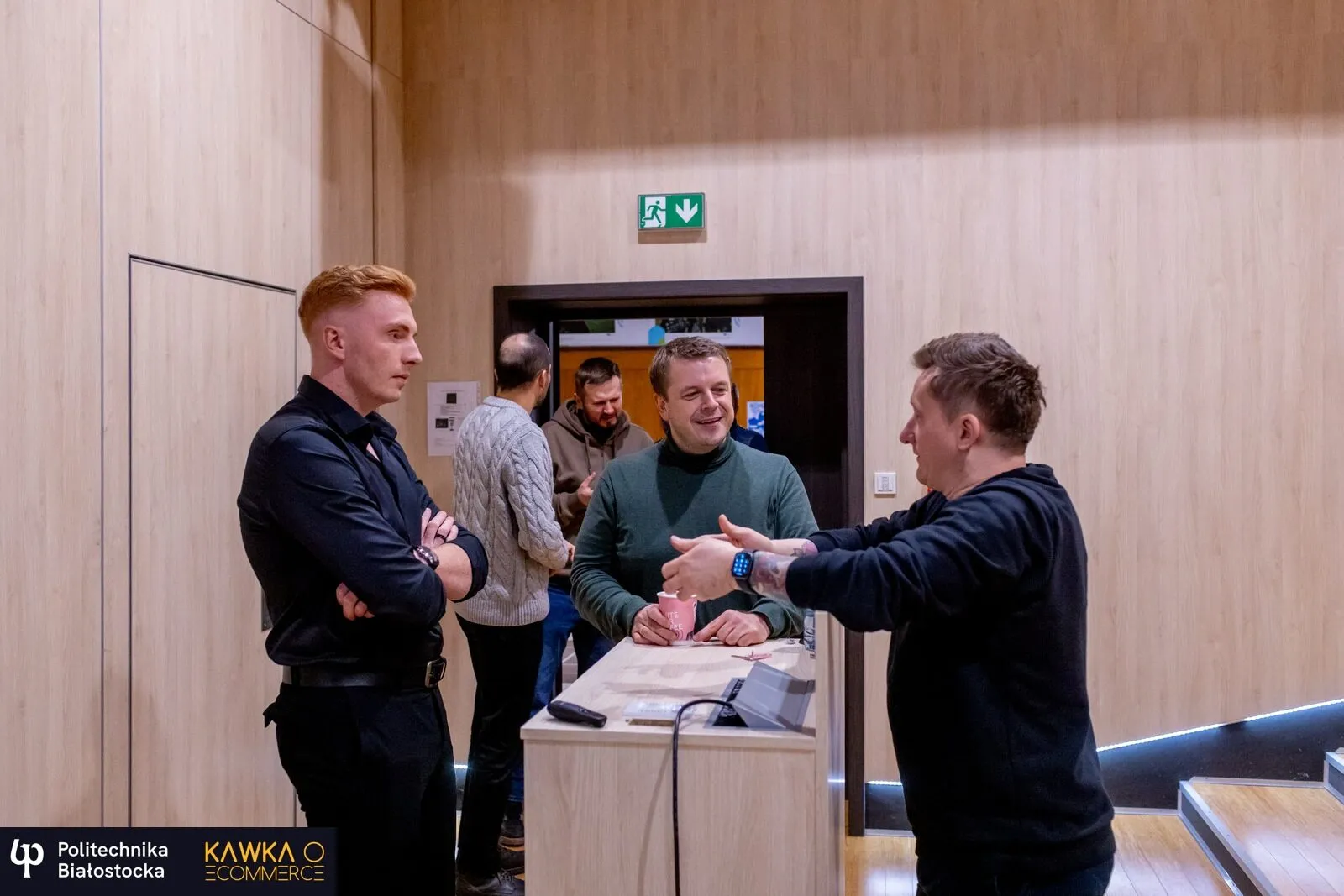Czterech uczestników rozmawia przy stoliku w kuluarach spotkania Kawka o e‑commerce na Politechnice Białostockiej.